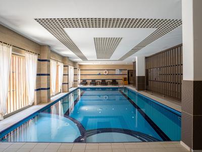 Wnętrze basenu z basenem, dużymi oknami i nowoczesnymi meblami.