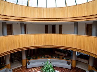 Elegancka okrągła strefa wypoczynkowa hotelu z dużymi sofami pod szklaną kopułą.