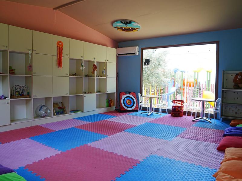 Jasny pokój zabaw z kolorowymi matami piankowymi i otwartymi półkami, widok na taras.