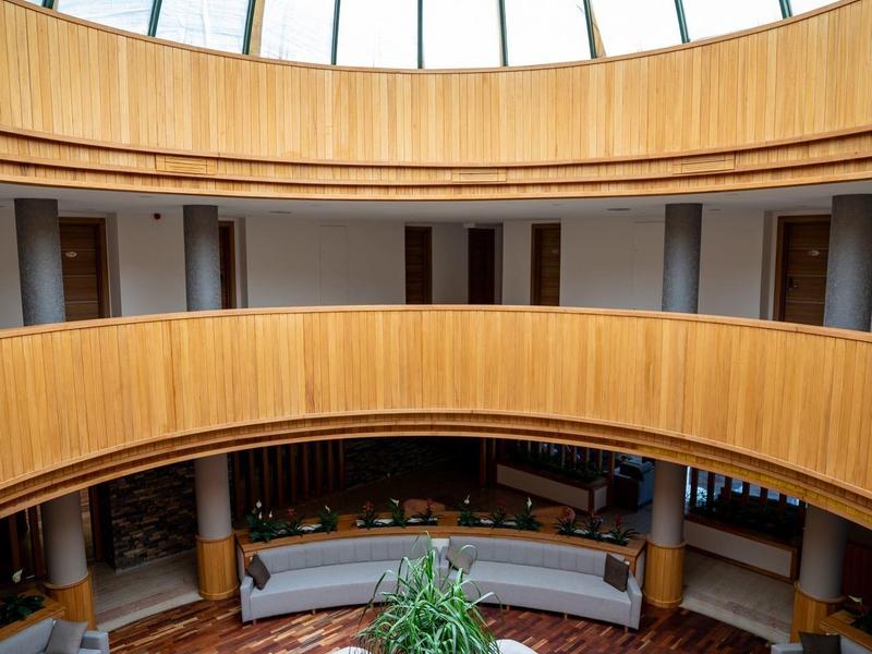 Elegancka okrągła strefa wypoczynkowa hotelu z dużymi sofami pod szklaną kopułą.