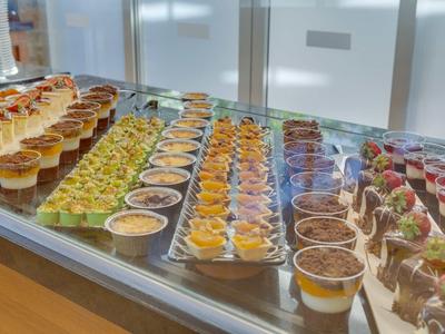 Buffet with various small desserts in glasses, neatly arranged in rows.