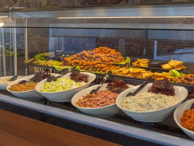 Buffet with various hot and cold dishes presented in white bowls and trays.