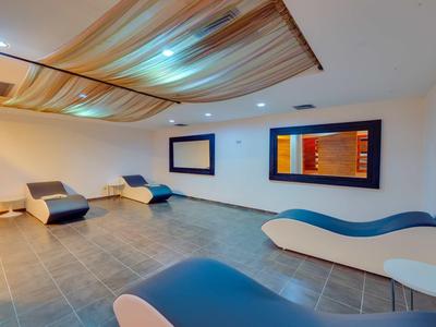 Modern relaxation room with wave-shaped loungers and decorative ceiling in warm tones.