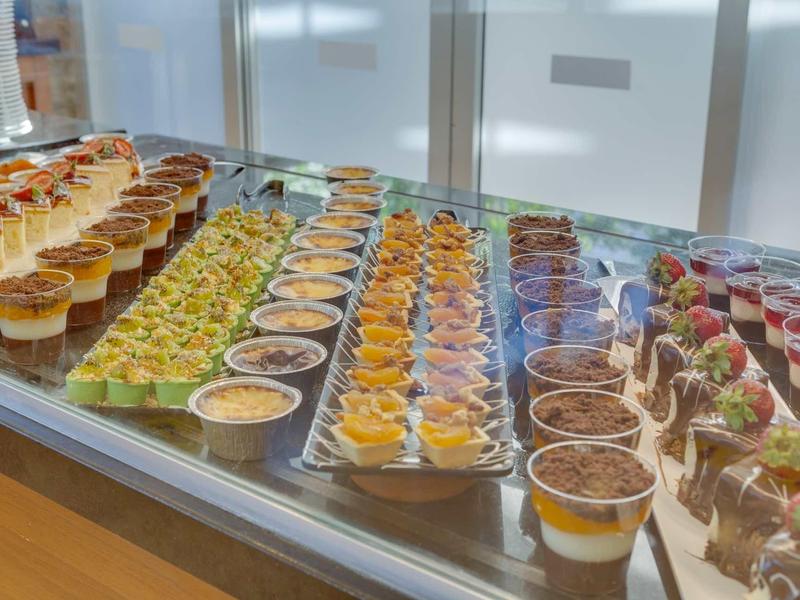 Buffet with various small desserts in glasses, neatly arranged in rows.
