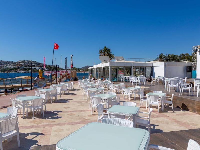Hotel outdoor terrace with white tables and chairs beside the sea