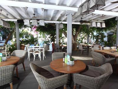 Terrasse extérieure d'un café confortable avec des tables rondes en bois et des chaises en osier sous un auvent blanc