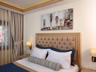 Camera d'albergo accogliente con testata imbottita, lampade da comodino e decorazione murale.