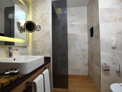 Bagno moderno con lavabo, specchio illuminato e cabina doccia separata con parete in vetro.