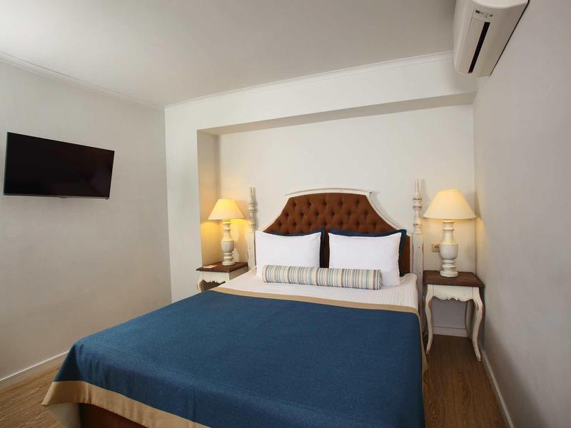 Camera d'hotel accogliente con letto matrimoniale, comodini e TV a parete.