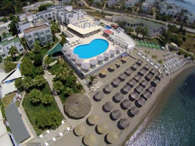 Complesso alberghiero con piscina, ombrelloni in spiaggia e vista mare.