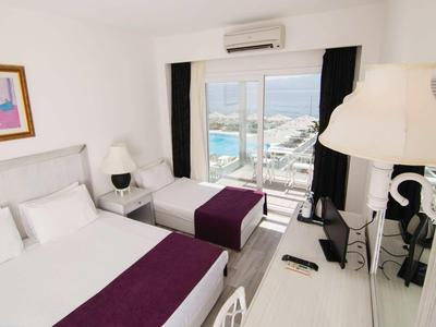 Camera d'hotel moderna con due letti, arredi bianchi e vista sul porto.