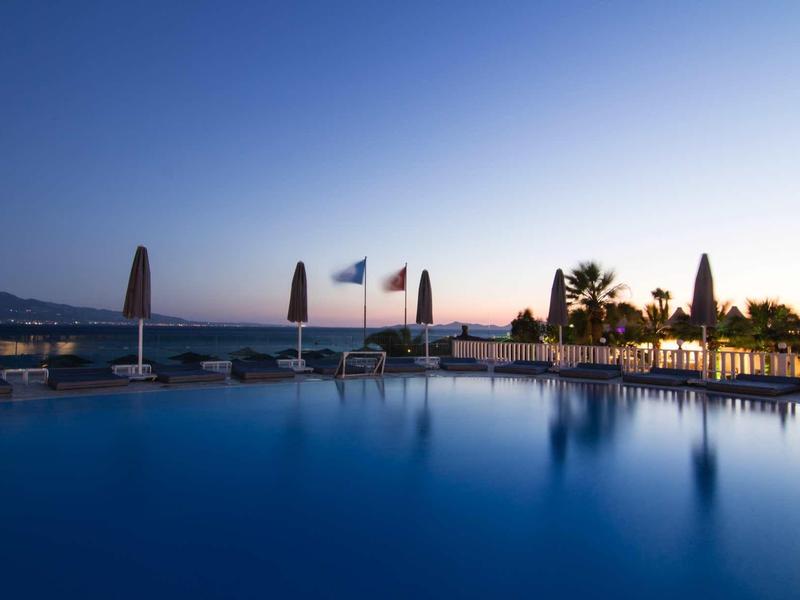 Zona piscina tranquilla al tramonto con lettini e palme in hotel.