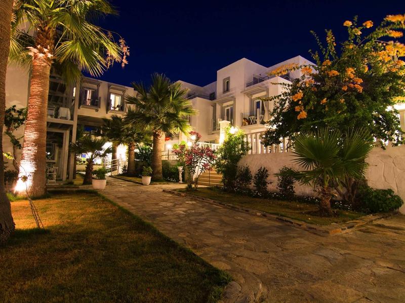 Sentiero del giardino illuminato con palme davanti a un edificio alberghiero pluripiano di notte