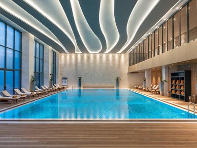 Modern indoor pool with indirect lighting and spacious lounge areas.