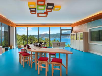 Modern dining room with large wooden table, red chairs, and panoramic windows overlooking the lake.