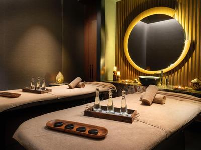 Elegant spa room with two massage tables, warm lighting, and decorative elements.