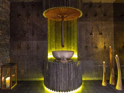 Atmospheric hotel bathroom fountain with dark stone and warm lighting.