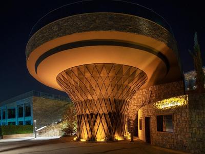 Illuminated modern hotel lobby entrance at night with a round roof structure.