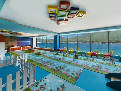 Colorful indoor play area with game tables and large windows overlooking lake and mountains.