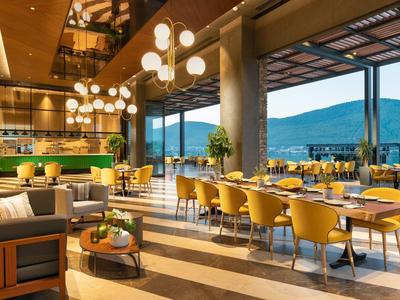 Modern restaurant with yellow chairs and panoramic mountain view in daylight.
