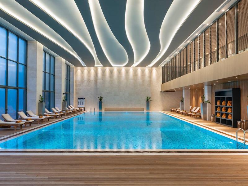 Modern indoor pool with indirect lighting and spacious lounge areas.