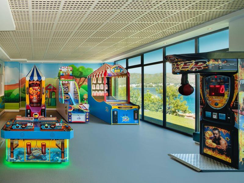 Bright arcade room with various games and large windows showing mountain views.