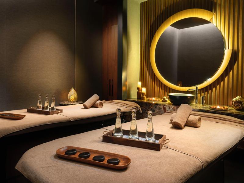 Elegant spa room with two massage tables, warm lighting, and decorative elements.