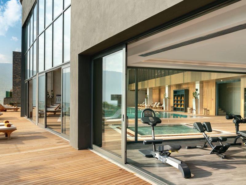 Modern gym overlooking terrace and sea in a hotel.