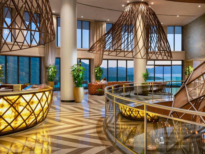 Luxurious hotel lobby with modern lighting, large windows, and a sea view.