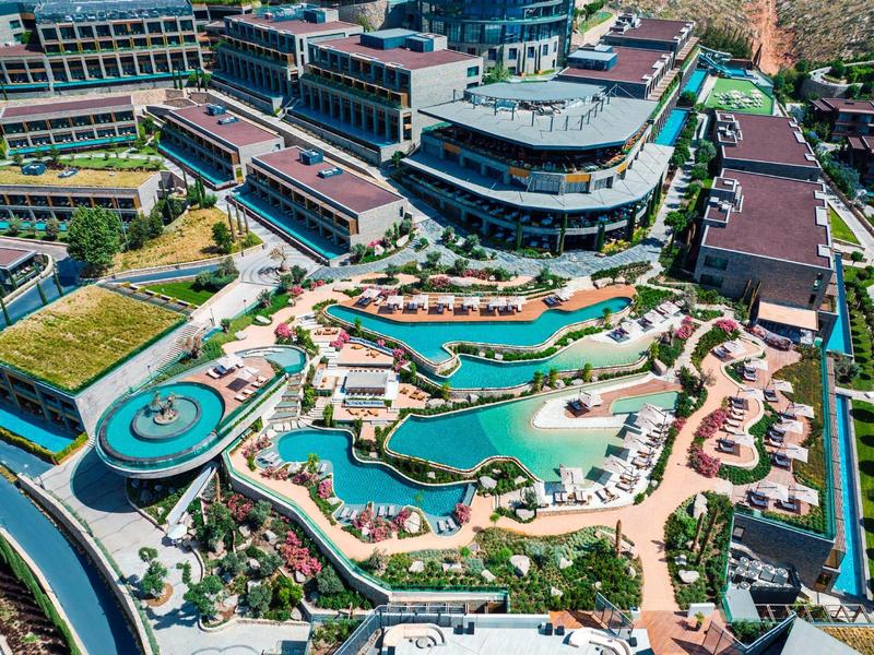 Aerial view of a luxury hotel resort with multiple pools and green areas.