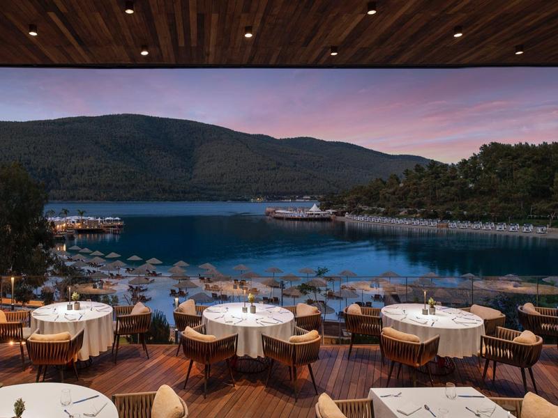 Restaurant terrace overlooking a bay and hills at sunset.