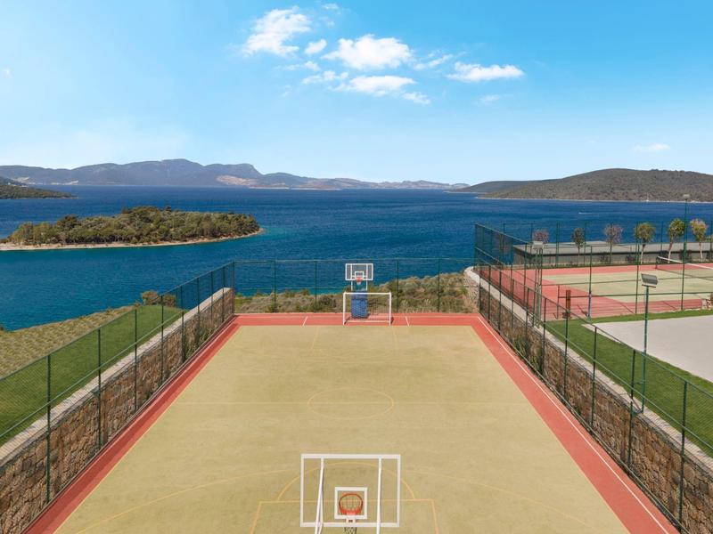 Outdoor basketball court overlooking a large blue body of water and islands.