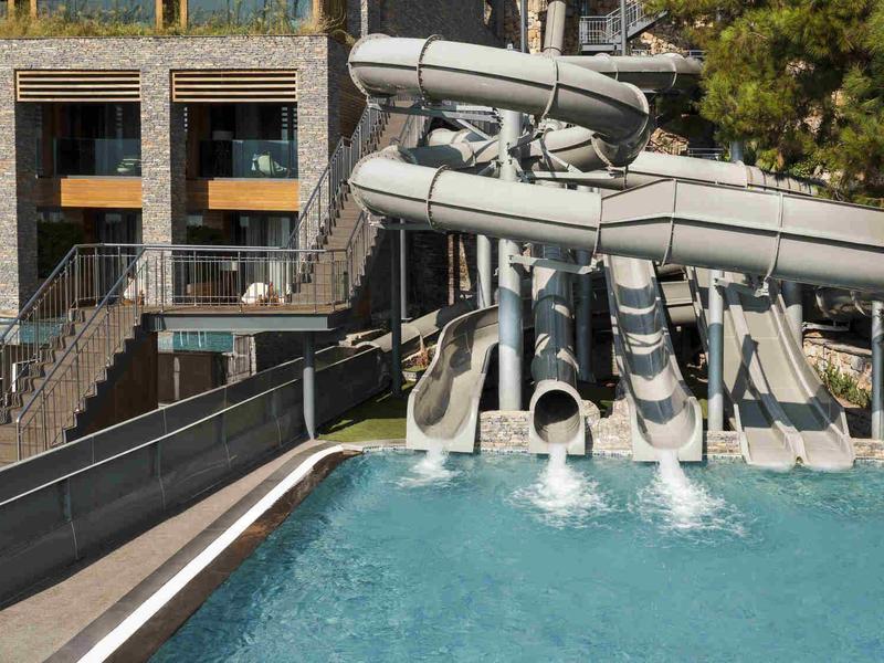 Multiple water slides empty into a pool in front of a hotel building.