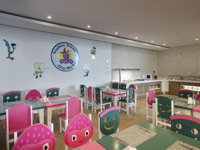 Salle à manger lumineuse pour enfants avec chaises colorées, tables et décorations murales ludiques.