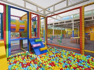 Aire de jeux intérieure avec piscine à balles colorées et structures d'escalade dans un hôtel.