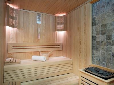 Sauna en bois chaleureux avec sièges, serviettes et poêle en pierres.