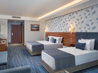 Chambre d'hôtel moderne avec deux lits, décoration bleue, accents en bois et mur à motifs.