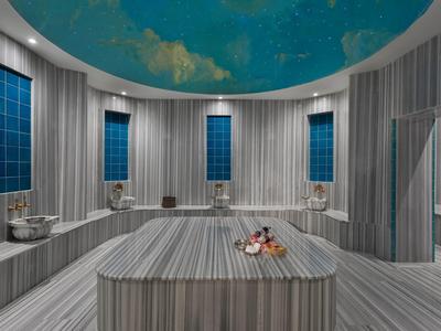 Salle de spa moderne avec sièges rayés, colonnes et plafond bleu avec motif nuages.