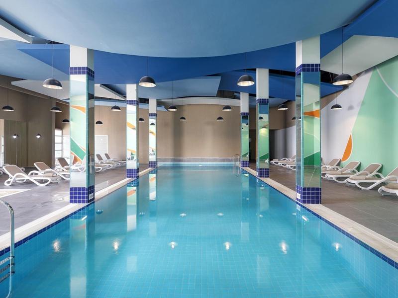 Piscine intérieure d'hôtel avec eau bleue, chaises longues et design moderne