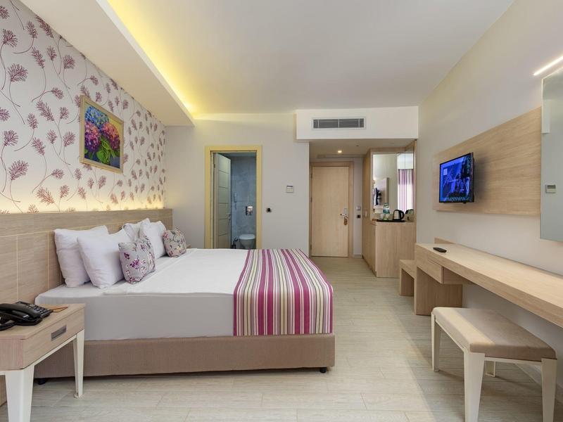 Chambre d'hôtel moderne avec un grand lit, une télévision, un bureau et un éclairage doux.