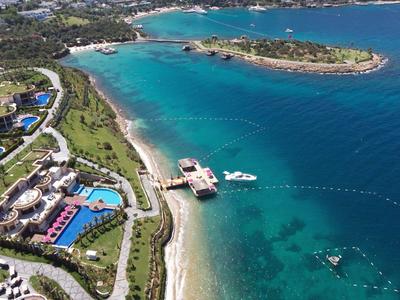 Aerial view of a coastal resort with beach, buildings, and clear turquoise water.