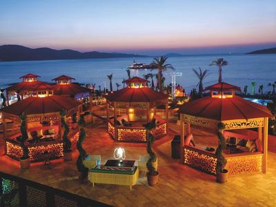 Evening view of a resort with illuminated gazebos overlooking the sea.