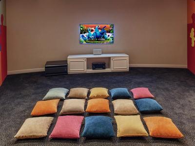 Cozy home theater room with comfortable cushions arranged on the floor in front of a wall-mounted TV.