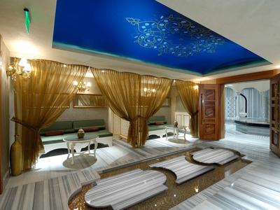 Luxurious spa area with marble loungers, golden curtains, and blue-lit ceiling ornament.