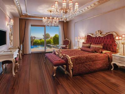 Elegantní hotelový pokoj s královskou postelí a výhledem na bazén a zahradu.