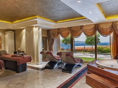 Luxurious spa area with massage tables, hot tub, and panoramic windows overlooking the sea.