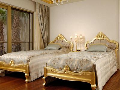 Elegant hotel room with two gold-trimmed single beds and wooden floor