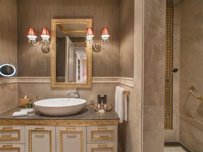Elegant bathroom with vanity, round sink, gold-framed mirror, and separate shower area.