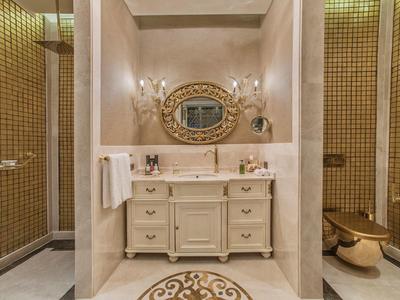 Elegant bathroom with marble vanity, oval mirror, and gold fixtures.