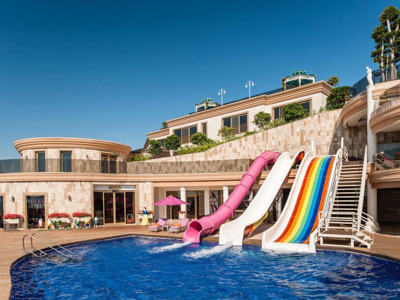 Hotel with multiple water slides, swimming pool, and sunny sky.